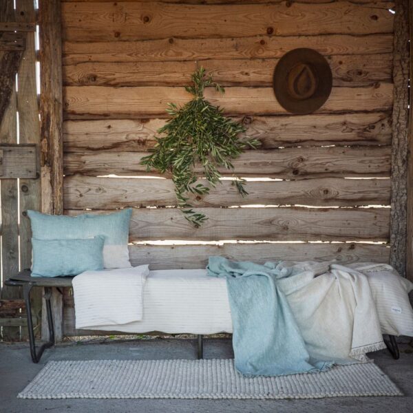 Tapis en laine bouclée écrue, modèle TEBBLES coloris Cream Coussin et plaid en coloris Aqua, thème INDY