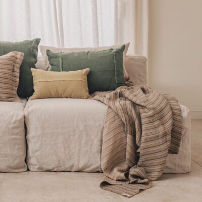 Coussins en lin HECTOR 40x60cm, HORACE 50x50cm, HYPOLITE 25x40cm, coloris KAKI et SAVANE, thème HANDMADE, avec coussin en lin MAMA 40x60cm et plaid MAYDAY, coloris Isatys, thème BELLAGIO, sur canapé en lin coloris Chalk, ligne SLOW, module d'angle COIN et chauffeuse SOLO