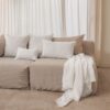 Coussins en lin HECTOR 40x60cm, HORACE 50x50cm, HYPOLITE 25x40cm, coloris WHITE, thème HANDMADE, avec coussin CROSS et plaid COMEBACK en lin, coloris Snowy, thème FARM LIFE, sur canapé en lin coloris Naturel, ligne SLOW, module d'angle COIN et chauffeuse SOLO
