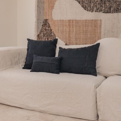 Coussins en lin HECTOR 40x60cm, HORACE 50x50cm, HYPOLITE 25x40cm, coloris NIGHT, thème HANDMADE, tapis BOHEMIAN âme philo en tenture murale, sur canapé en lin coloris CHALK, ligne SLOW, module d'angle COIN et chauffeuse SOLO