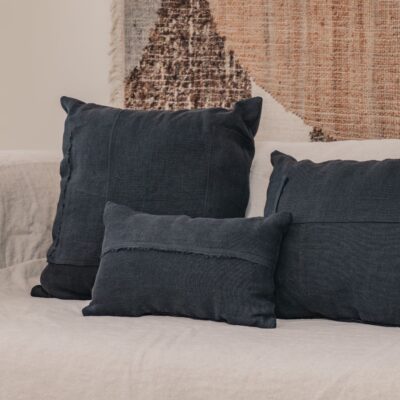 Coussins en lin HECTOR 40x60cm, HORACE 50x50cm, HYPOLITE 25x40cm, coloris NIGHT, thème HANDMADE, tapis BOHEMIAN âme philo en tenture murale, sur canapé en lin coloris CHALK, ligne SLOW, module d'angle COIN et chauffeuse SOLO