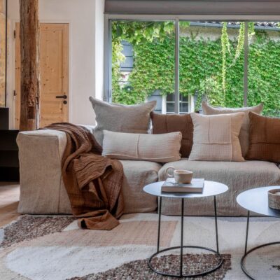 Coussins en coton et lin NIRVANA 30x70cm et NAXOS 50x50cm, et plaid NATTE 140X200CM, coloris Crème et Café, thème Couleurs Locales sur canapé en lin GROSSE TRAME, composition COIN et SOLO de la ligne URBAN, tapis âme philo BOHEMIAN coloris Natural