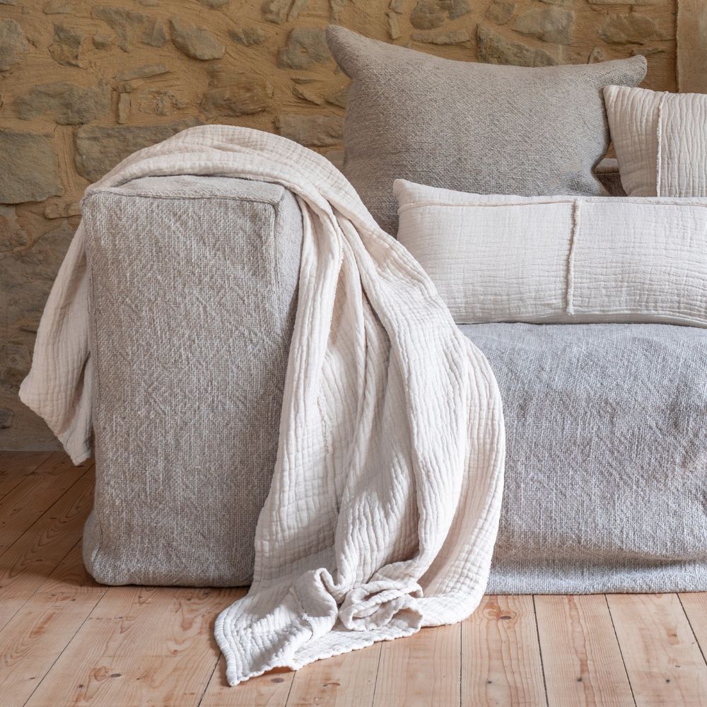 Coussins en coton et lin NIRVANA 30x70cm et NAXOS 50x50cm, et plaid NATTE 140X200CM, coloris Crème, thème Couleurs Locales sur canapé en lin GROSSE TRAME, composition COIN et SOLO de la ligne URBAN