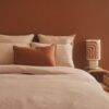 Linge de lit en satin de coton coloris Coton, housse de couette Chic, taie d'oreiller 65x65cm CHARME, taie d'oreiller 50x70cm CHERRY, coussin TAORMINA, coloris Sienna, thème PIGMENTS, lampe PSYCHOSE en coton tufté avec pied en céramique TERRAM1 âme philo